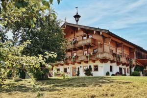 a large wooden house in a field with a tree at Apartment Wachinghof in Reith bei Kitzbühel