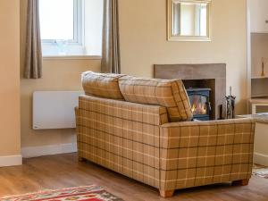 een bank in een woonkamer met een open haard bij Dovecote - Uk47887 in Keilour
