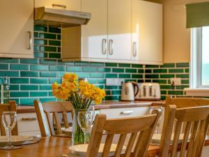een keuken met een tafel met gele bloemen in een vaas bij Dovecote - Uk47887 in Keilour