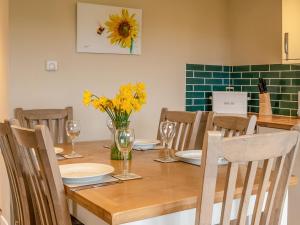 een eetkamer met een houten tafel met gele bloemen bij Dovecote - Uk47887 in Keilour +11 foto's