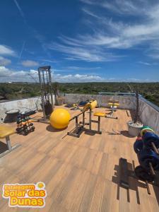 a gym with yellow equipment on a wooden deck at Estalagem Solar das Dunas in Pirambu
