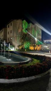 a building with a fountain in front of a building at night at Apartamento VOG praia do Sul ilhéus in Ilhéus