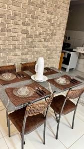 a dining table with four chairs and a brick wall at Apartamento VOG praia do Sul ilhéus in Ilhéus