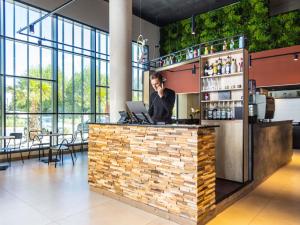 un bar dans un restaurant avec un homme qui parle au téléphone dans l'établissement Ibis Marseille Marignane Technopole, à Marignane