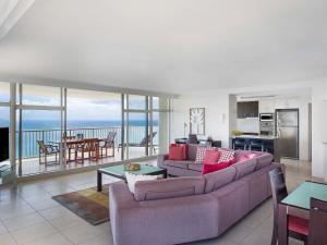 een woonkamer met een bank en een tafel en een keuken bij BreakFree Imperial Surf in Gold Coast