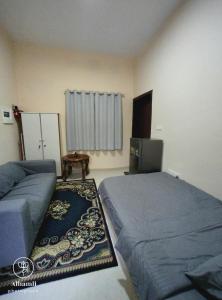 アル・アインにあるSolo comfort stay 1のベッド2台、冷蔵庫、ラグのある寝室