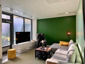 a living room with a green wall and a television at Lahtihovi in Lahti