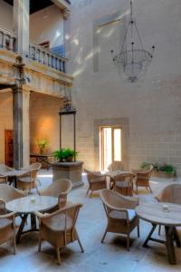 un restaurante con mesas y sillas y una lámpara de araña en Palacio Carvajal Girón en Plasencia