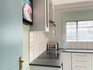 a kitchen with a stove and a microwave at Stay Arcadia Guest House in Pretoria