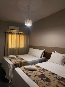 een slaapkamer met 2 bedden en een kroonluchter bij Hotel Mamoan in Ilhéus +10 foto's