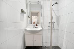 ein weißes Badezimmer mit Waschbecken und Dusche in der Unterkunft Spaceous room in Majorstuen central Oslo by subway in Oslo