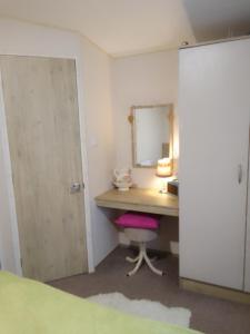 a bedroom with a desk with a mirror and a pink chair at Lovely new private caravan situated at park dean resorts ,st margerets at cliffe white cliffs kent in St Margarets at Cliff