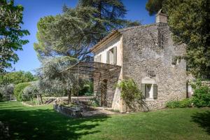 ein altes Steinhaus auf einem Feld mit Bäumen in der Unterkunft Le Hameau des Sources Lourmarin Luberon in Apt