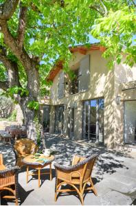 eine Terrasse mit einem Tisch und Stühlen unter einem Baum in der Unterkunft Le Hameau des Sources Lourmarin Luberon in Apt