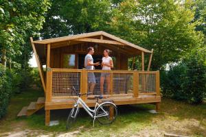 a man and woman standing in a gazebo with a bike at Camping Capfun La Bretèche in Les Épesses