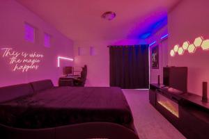 een paarse slaapkamer met een bed en een televisie bij Modern 2BR 2BA Townhome 15 Min to DEN in Commerce City