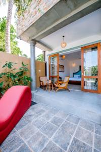 an outdoor patio with a red couch and chairs at Sithagi River Front Villa Weligama in Weligama