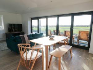 a living room with a table and chairs and a couch at Glynllifon 4 in Llanallgo