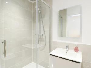 a white bathroom with a shower and a sink at Glynllifon 4 in Llanallgo +15 photos