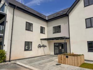 a white building with black windows and a courtyard at Glynllifon 4 in Llanallgo