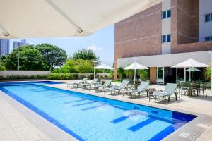 une piscine avec chaises et parasols à côté d'un bâtiment dans l'établissement Iu-á Hotel, à Juazeiro do Norte