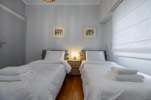 twee bedden in een kamer met witte lakens bij Daphnes Home Chalkida Central in Chalkida