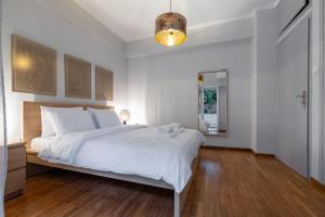 een slaapkamer met een groot wit bed en een houten vloer bij Daphnes Home Chalkida Central in Chalkida