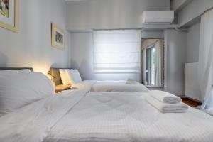 een witte slaapkamer met twee bedden en een raam bij Daphnes Home Chalkida Central in Chalkida