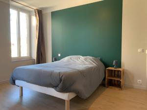 een bed in een slaapkamer met een groene muur bij Gîte Un Toit Pour Vous in Les Épesses