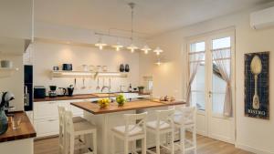 een keuken met een kookeiland met witte kasten en witte stoelen bij VILLA FRANCESCA 10, Emma Villas in Volterra