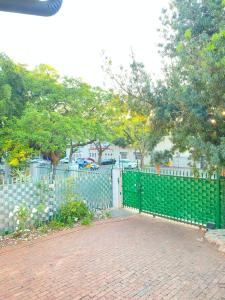 a green fence next to a brick walk way at Stay Arcadia Guest House in Pretoria