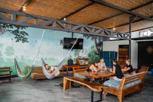 a group of people sitting in hammocks in a room at Sandy Toes Hostel in Sámara