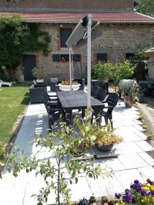 un patio avec une table, des chaises et un parasol dans l'établissement O p'tit nid à bulles, à Létricourt