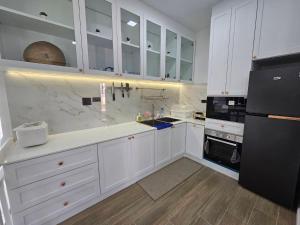 een keuken met witte kasten en een zwarte koelkast bij KARN E2 House Khaoyai in Mu Si