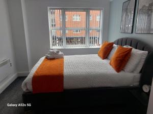 a bed with an orange and white comforter and a window at Aphrodite in Birmingham