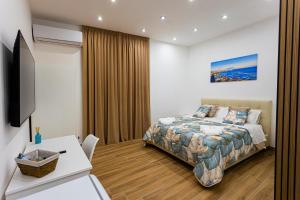 ein Schlafzimmer mit Bett, Schreibtisch und Fernseher in der Unterkunft Scio' Scio' in Neapel