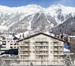 a hotel with snow covered mountains in the background at A&Y Signature Lodge St Moritz Pontresina Spa in Pontresina