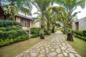a stone walkway with palm trees and a building at ONYX PARK RESORT Ubud in Ubud