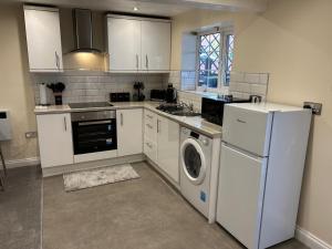 a kitchen with white cabinets and a washer and dryer at Studio 1 in Howden