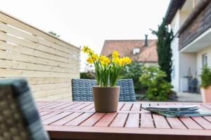een houten tafel met een vaas met gele bloemen erop bij Ferienwohnung Am Alpenblick in Lindau