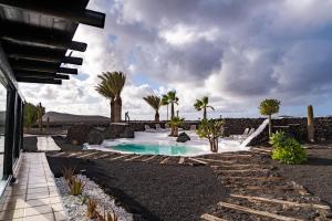 a swimming pool in a yard with palm trees at La Geria Suites in Yaiza