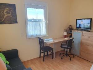una camera con scrivania, 2 sedie e TV di Sonniges Zimmer im Einfamilienhaus a Niederdorla