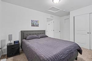 een slaapkamer met een bed en een dressoir met een nachtkastje bij Modern 2BR 2BA Townhome 15 Min to DEN in Commerce City