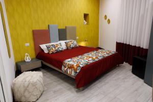 a bedroom with a bed with red sheets and a yellow wall at B&B Bifulco Boutique Rooms in Ottaviano