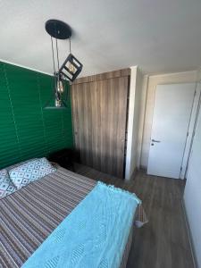 een slaapkamer met een bed met een groen hoofdeinde en een deur bij Estacionamiento, Céntrico y Cómodo in Chillán