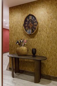 a clock on a wall next to a table with flowers at B&B Bifulco Boutique Rooms in Ottaviano