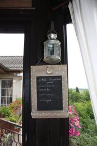 een bord aan de zijkant van een huis met een licht bij La Roulotte d'Arthur in Sercoeur