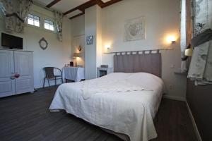 een slaapkamer met een wit bed en een tafel bij La Roulotte d'Arthur in Sercoeur