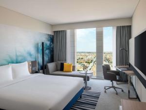 リヤドにあるNovotel Riyadh Sahafaの大きな白いベッドと机があるホテルの部屋