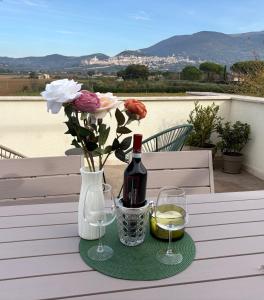 Assisi Panorama Luxe في أسيسي: زجاجة من النبيذ و مزهرية مع الزهور على الطاولة